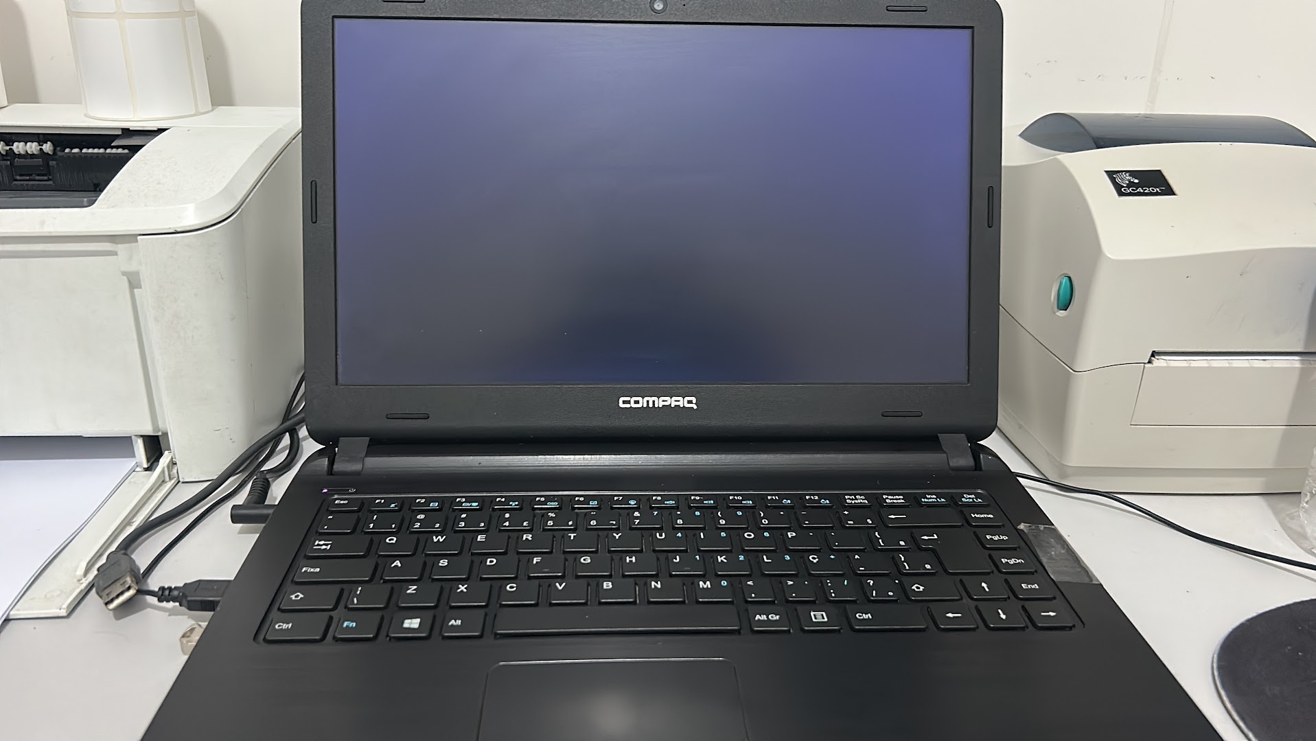 Notebook aberto para diagnóstico ao lado de impressoras